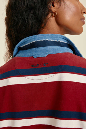 Close-up of a person wearing a red, white, and blue striped shirt with a brand logo.