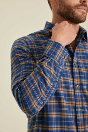 Man wearing a blue and orange plaid shirt against a beige background