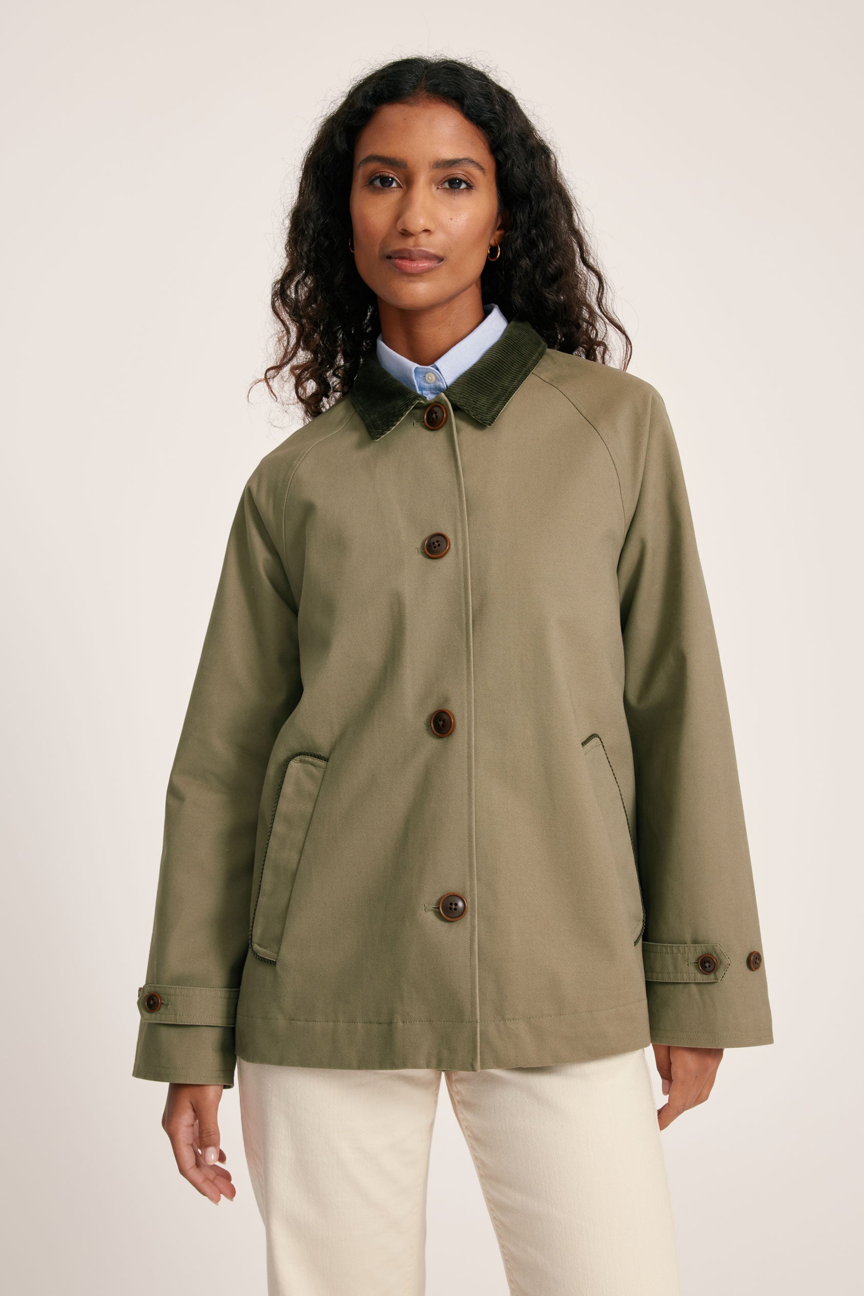 Woman wearing a green jacket with brown buttons on a white background