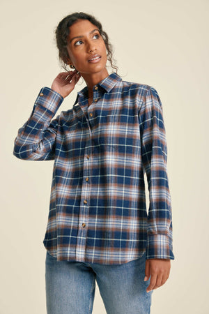 Woman wearing a plaid shirt and jeans on a beige background