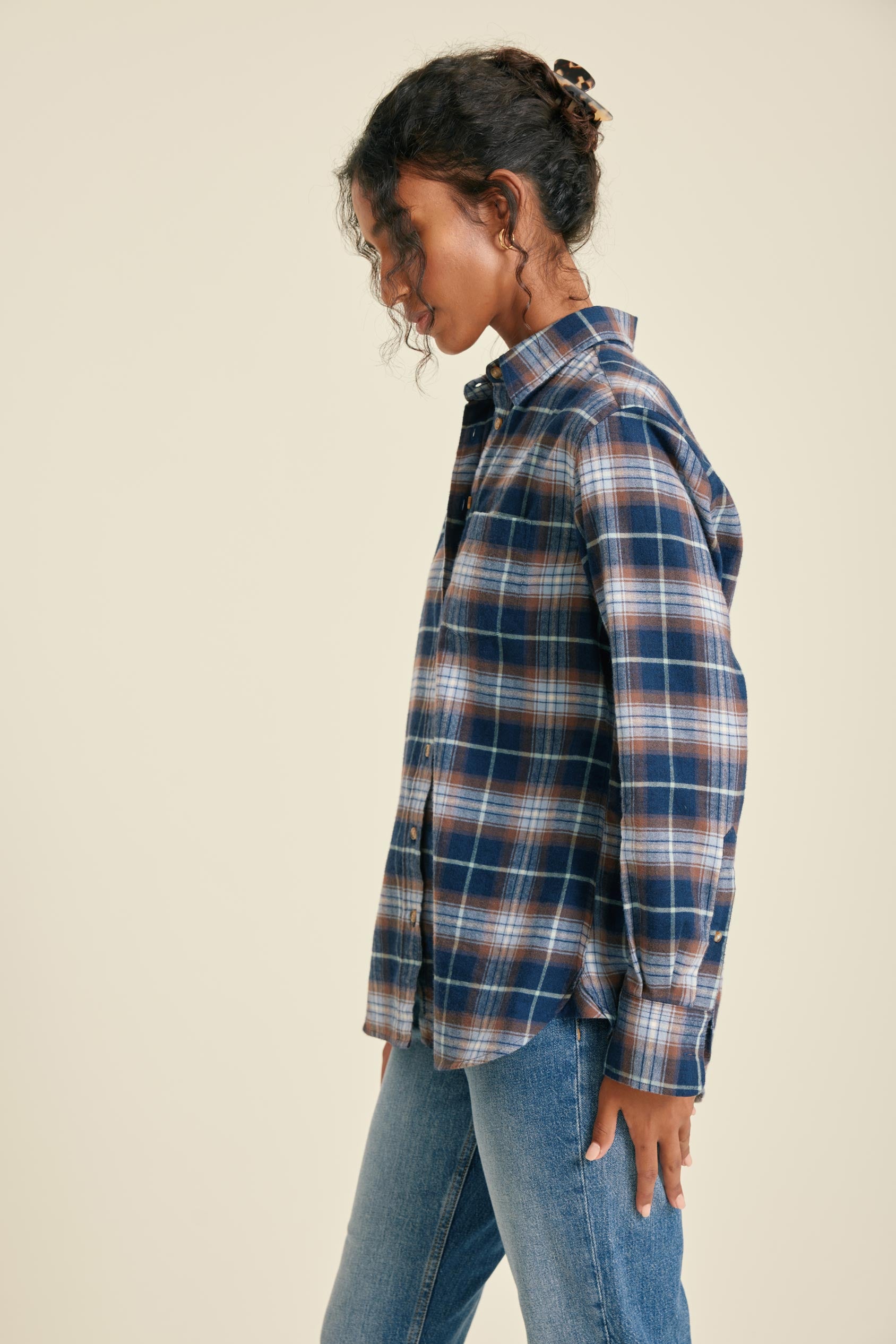 Person wearing a plaid shirt and jeans on a beige background