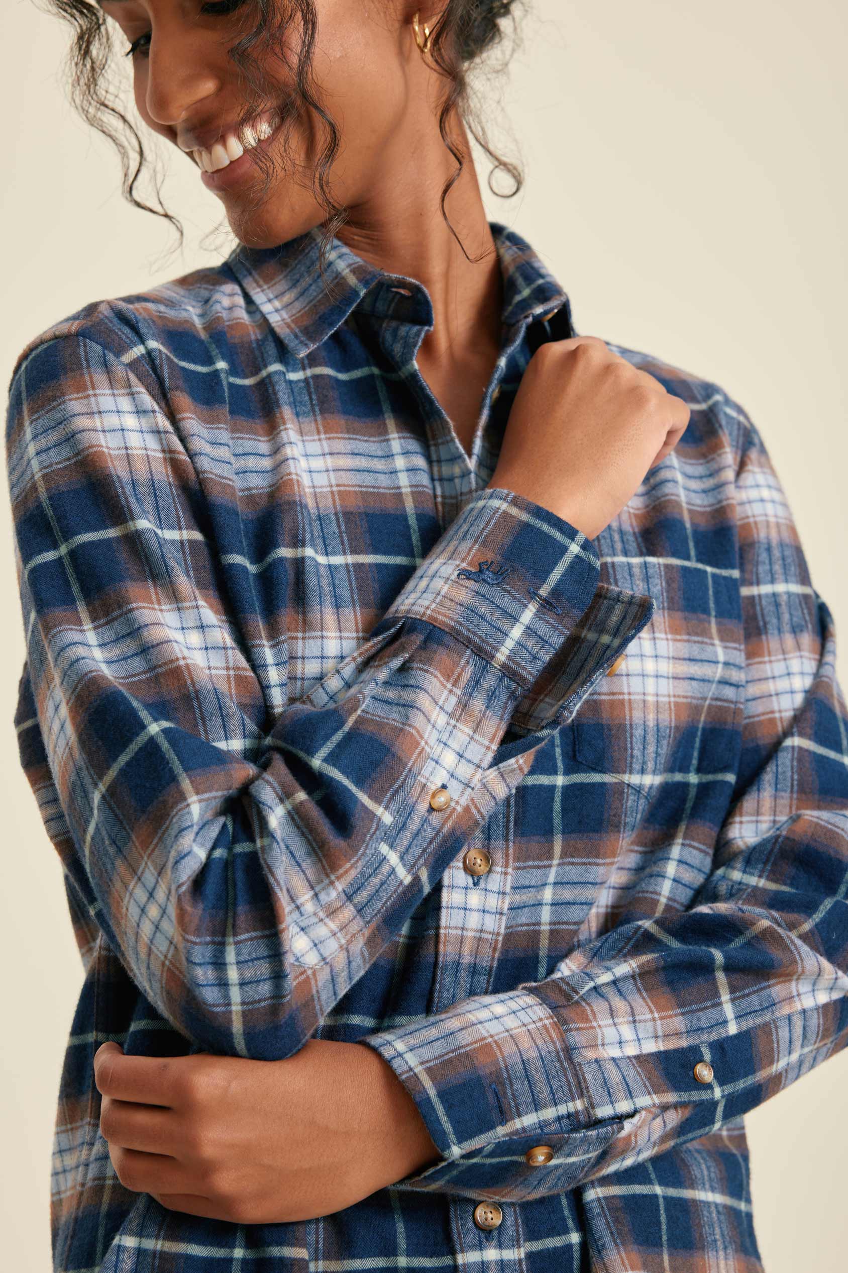 Woman wearing a blue plaid shirt against a beige background