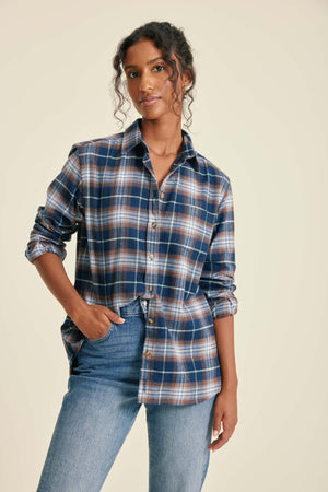 Woman wearing a plaid shirt and jeans on a beige background