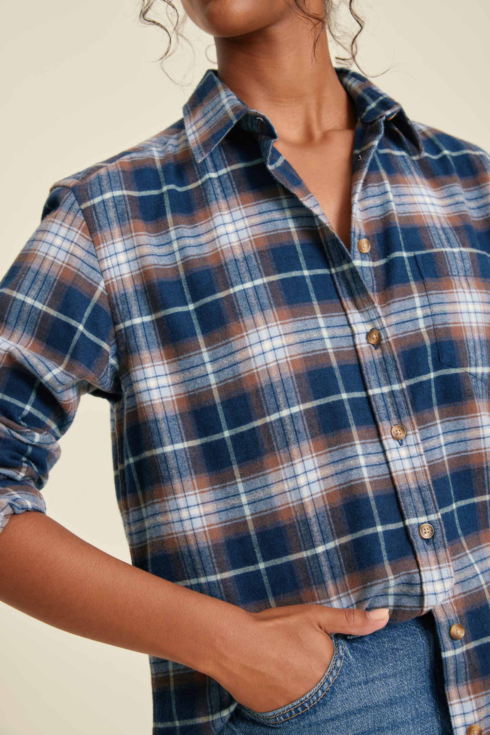 Person wearing a blue and brown plaid shirt with a neutral background