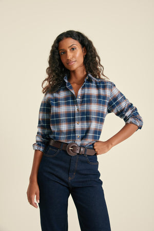 Woman wearing a plaid shirt and dark jeans on a beige background