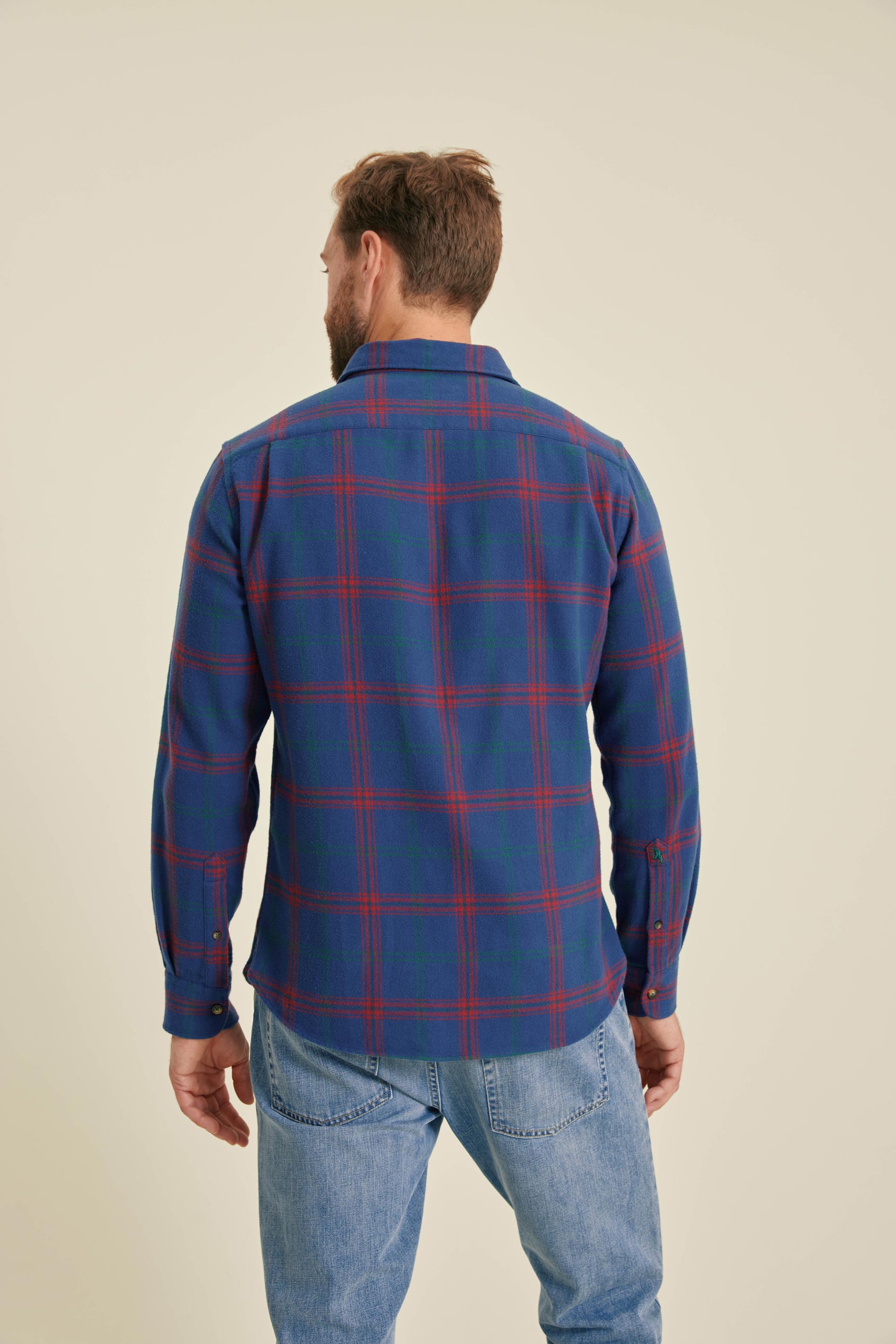 Man wearing a blue and red plaid shirt on a beige background