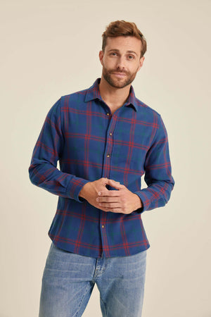 Man wearing a blue plaid shirt and jeans on a beige background