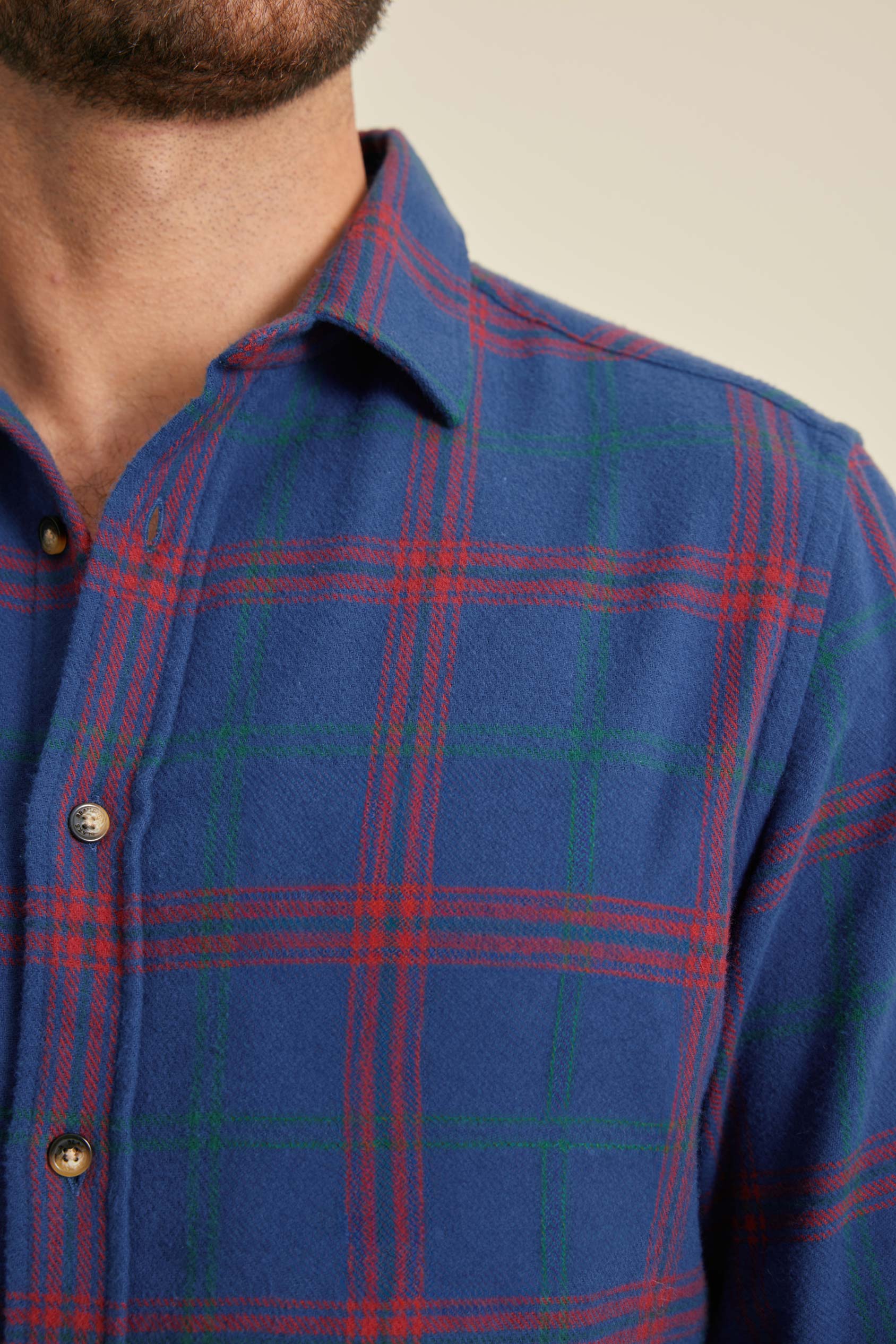 Close-up of a blue plaid shirt with red and green lines on a neutral background
