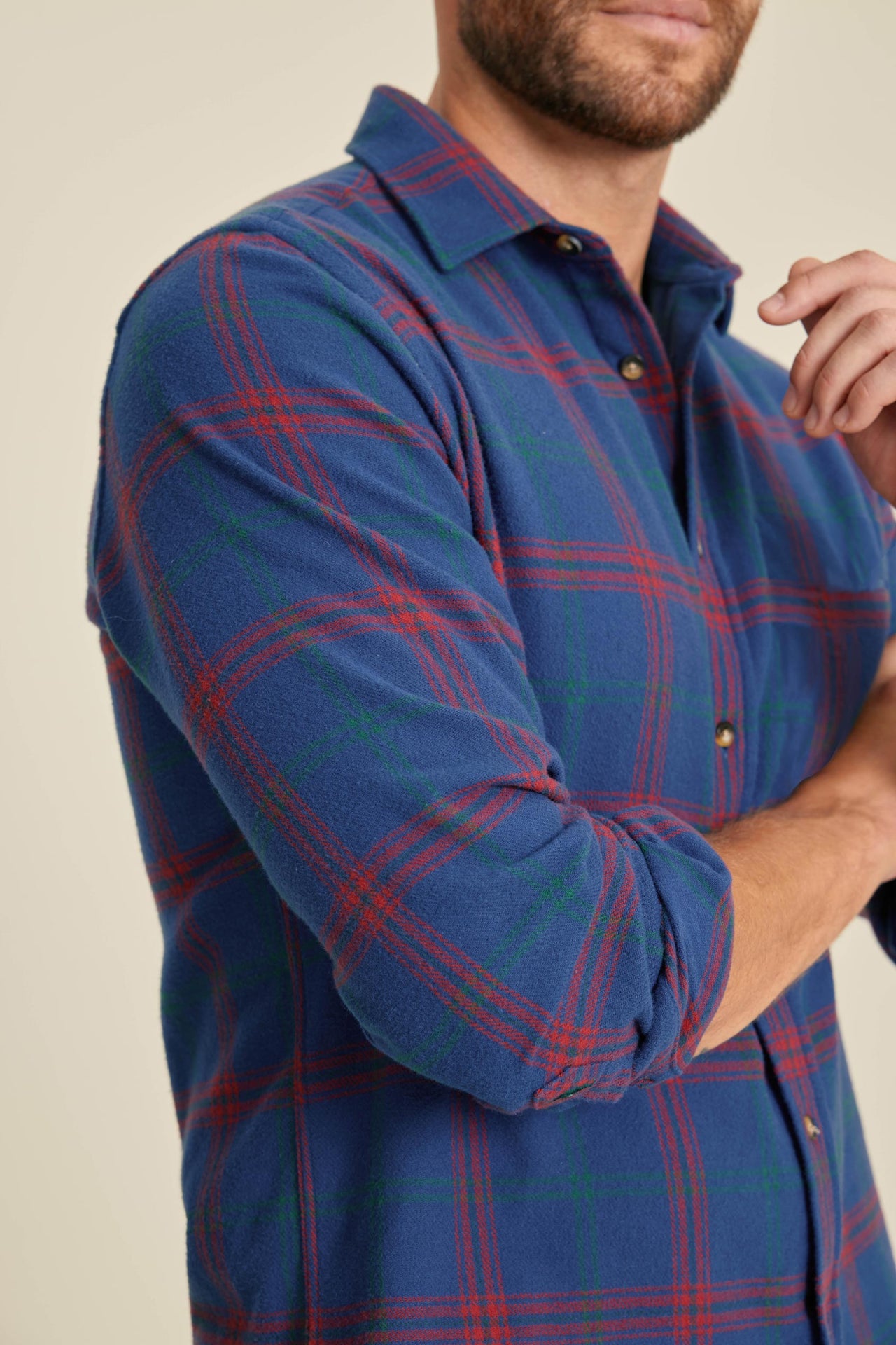 Man wearing a blue and red plaid shirt against a beige background
