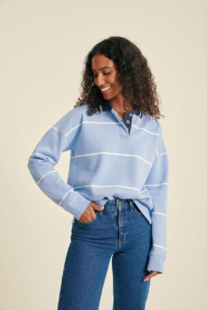 Woman wearing a blue striped sweater and jeans against a beige background