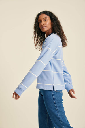Woman wearing a light blue striped sweater and jeans on a beige background