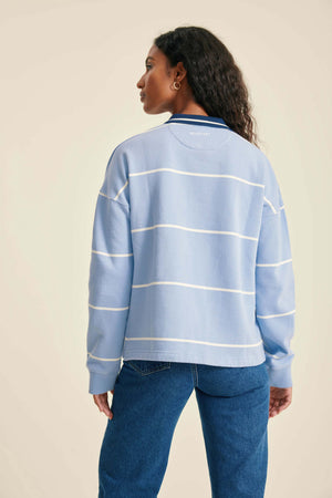 Person wearing a light blue striped sweater and blue jeans on a beige background