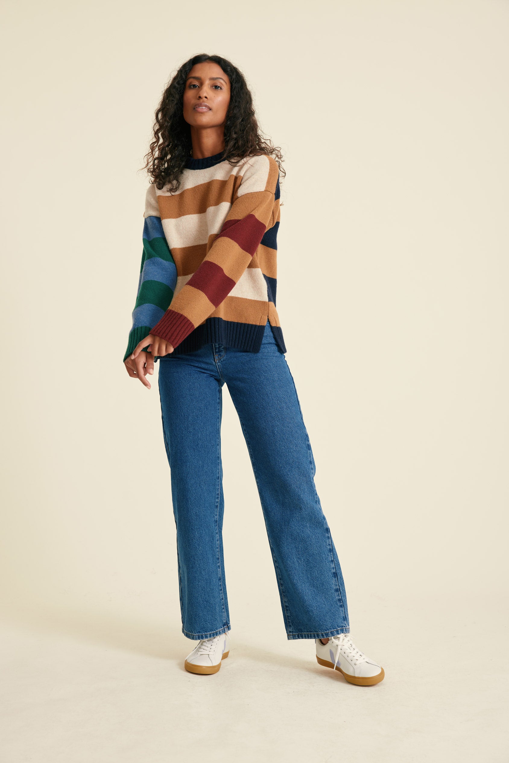 Woman wearing a colorful checkered sweater and blue jeans on a beige background