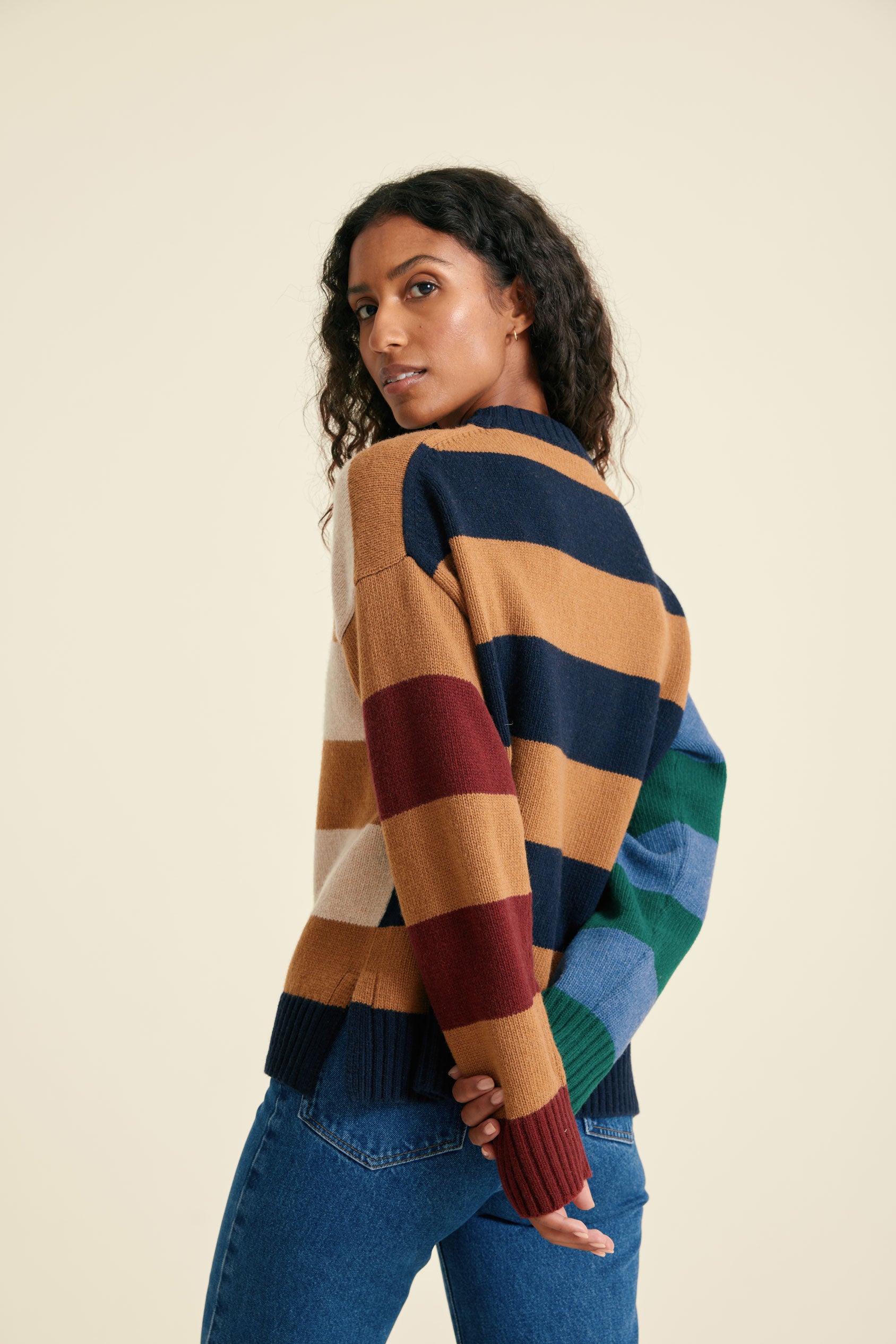 Woman wearing a multicolored striped sweater against a beige background