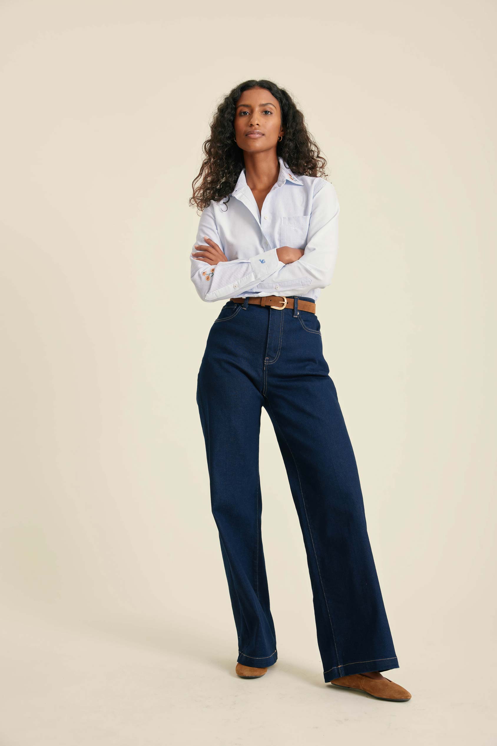 Woman wearing a white shirt and blue jeans on a beige background