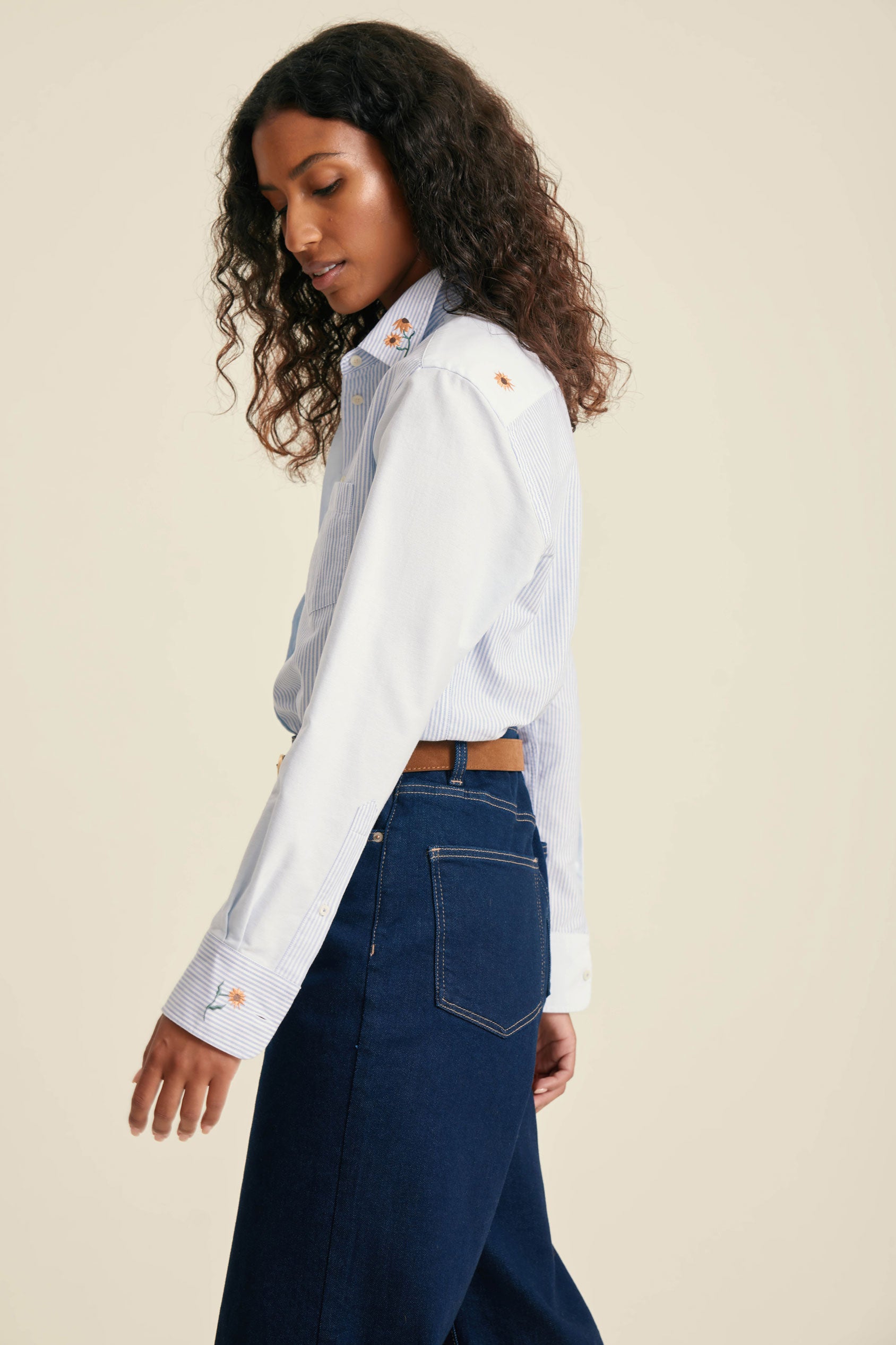 Woman wearing a white shirt and blue jeans on a beige background