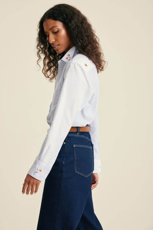 Woman wearing a white shirt and blue jeans on a beige background