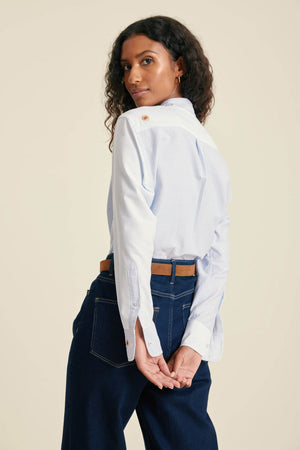 Woman wearing a white shirt and dark jeans on a beige background