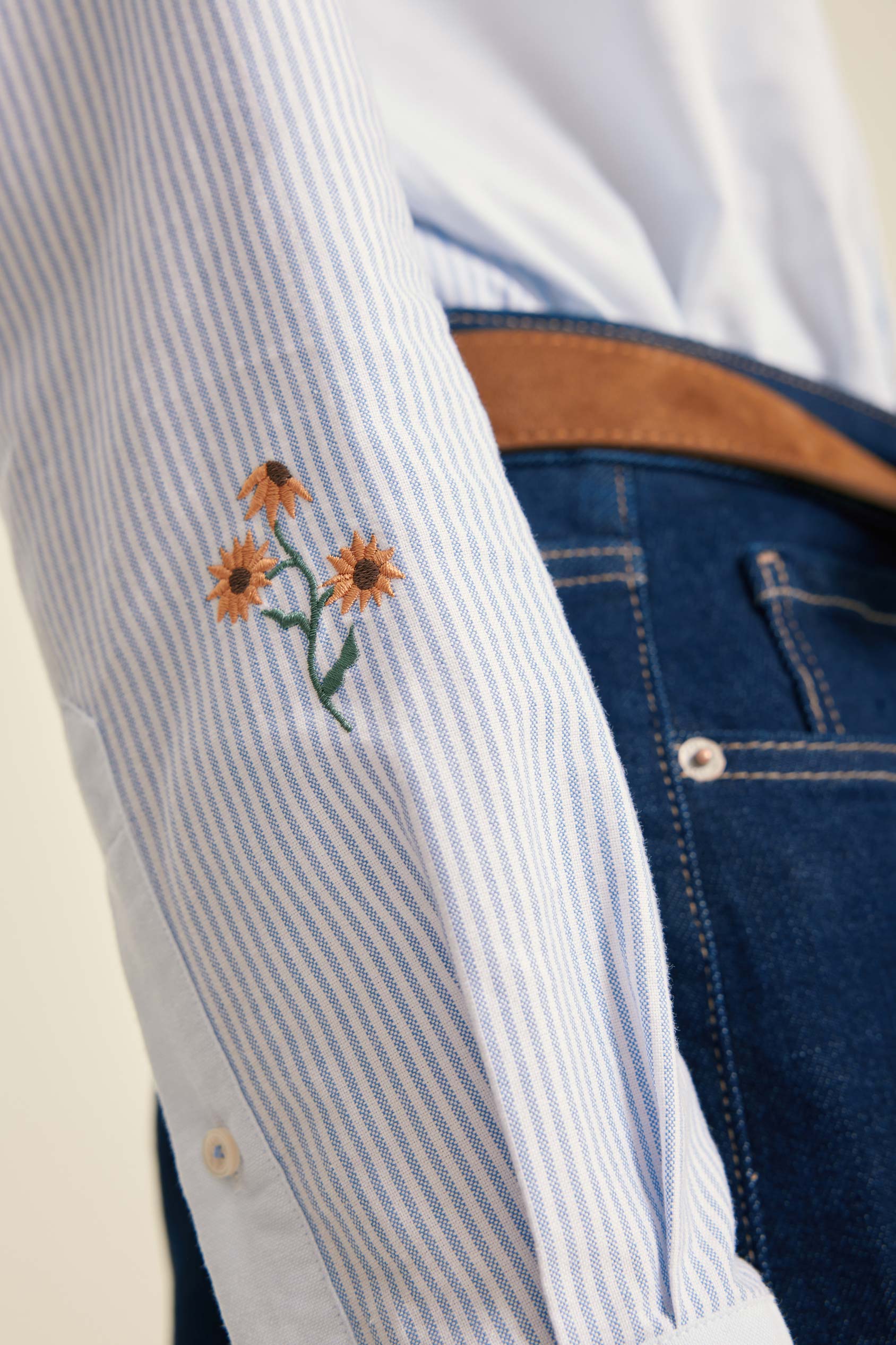 Close-up of a white shirt with embroidered flowers on a blue background
