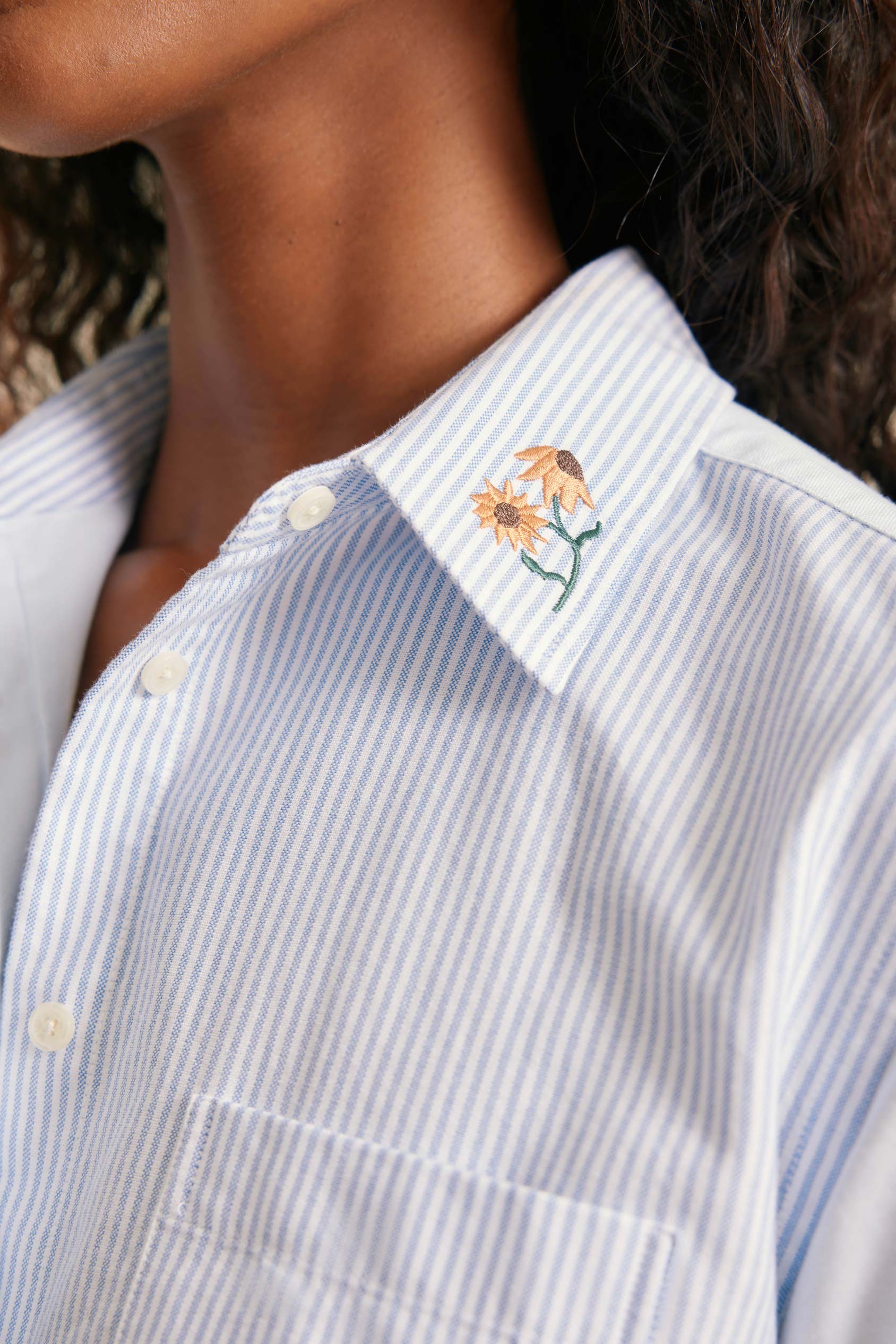 Close-up of a person wearing a shirt with floral embroidery on the collar.