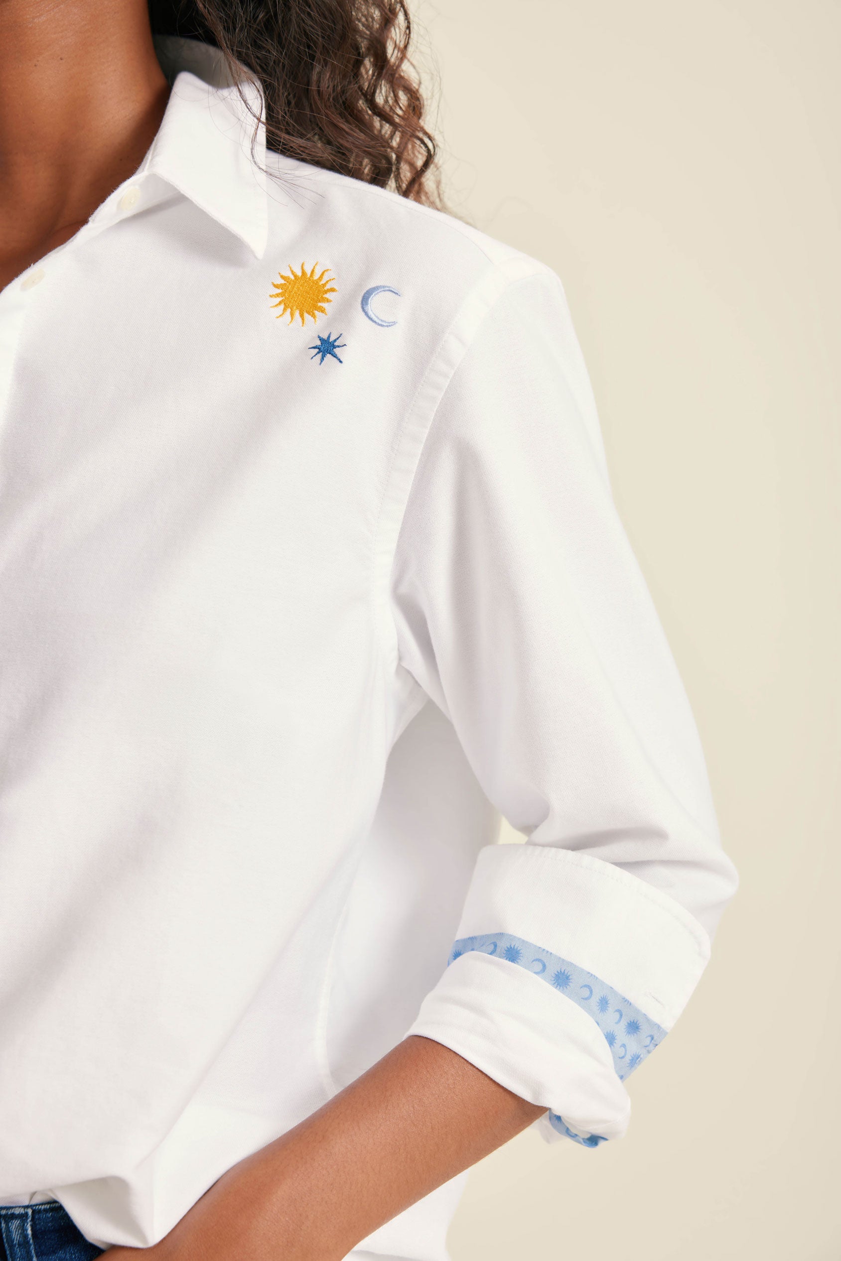 White shirt with embroidered designs on a neutral background