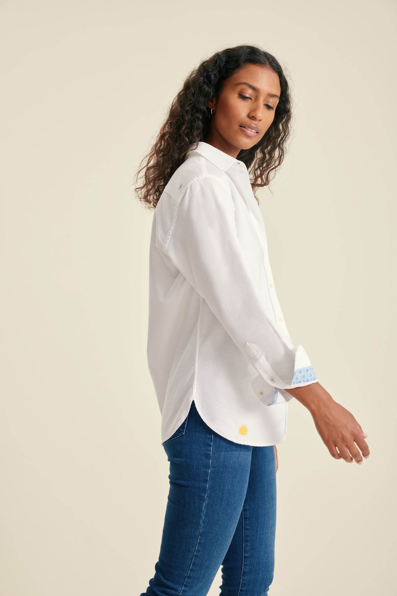 Woman wearing a white shirt and blue jeans on a beige background