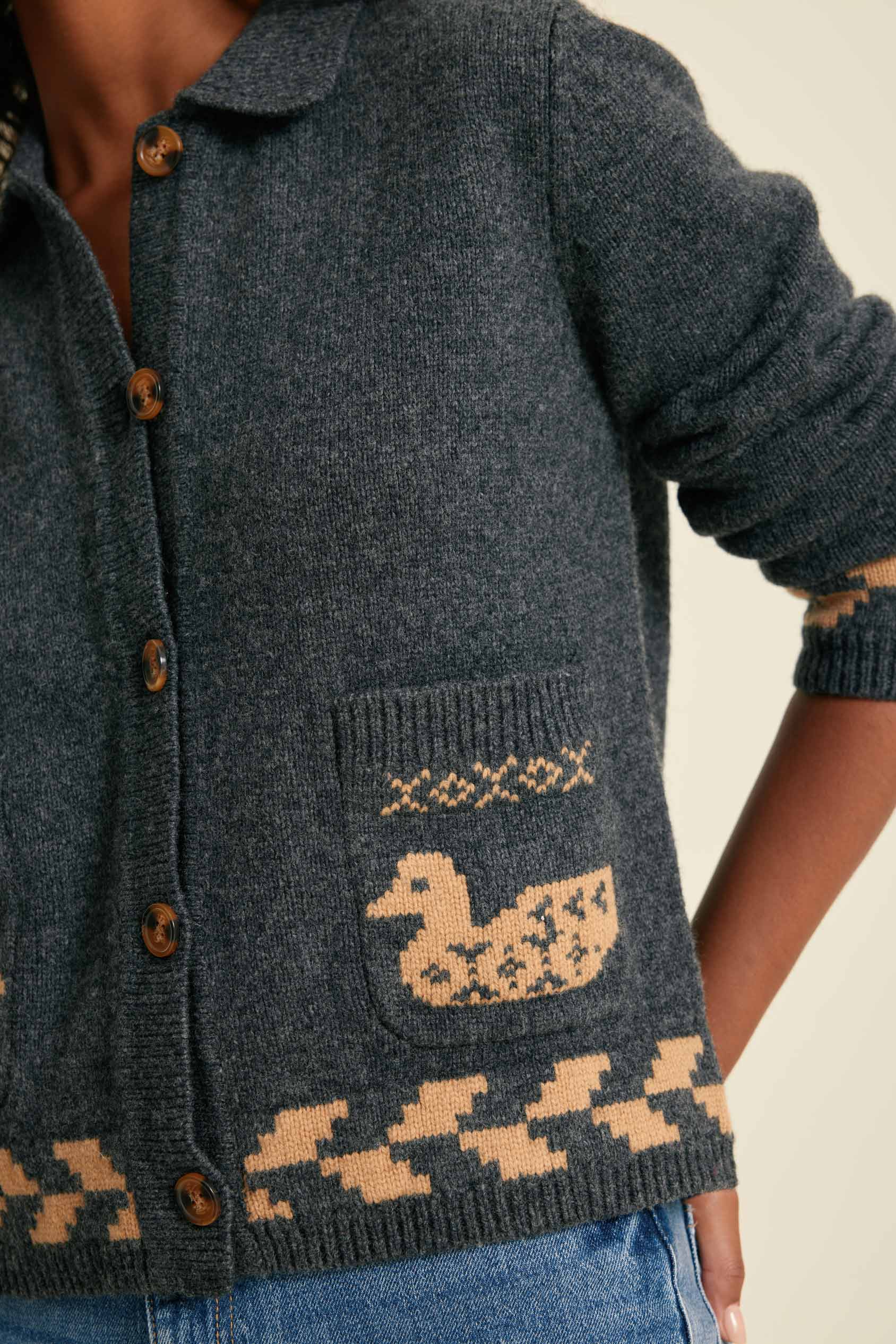 Dark blue knitted cardigan with a duck pattern on a neutral background