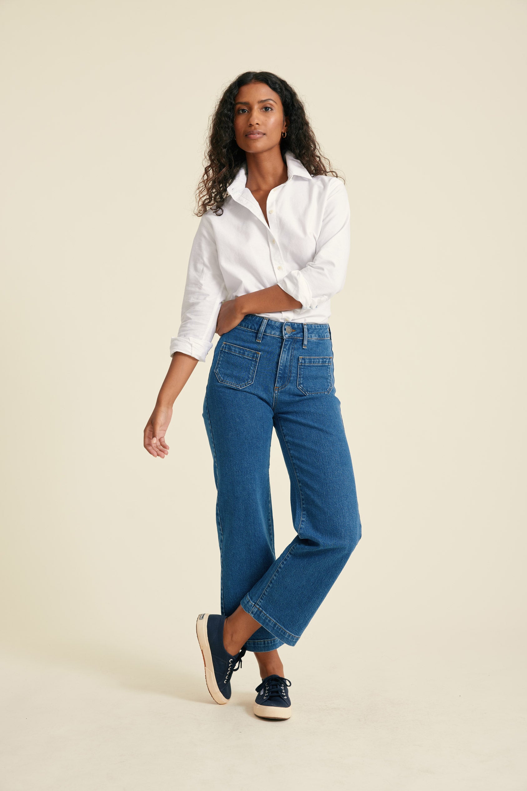 Woman wearing a white shirt and blue jeans on a beige background