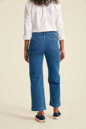 Person wearing blue jeans and a white shirt on a beige background