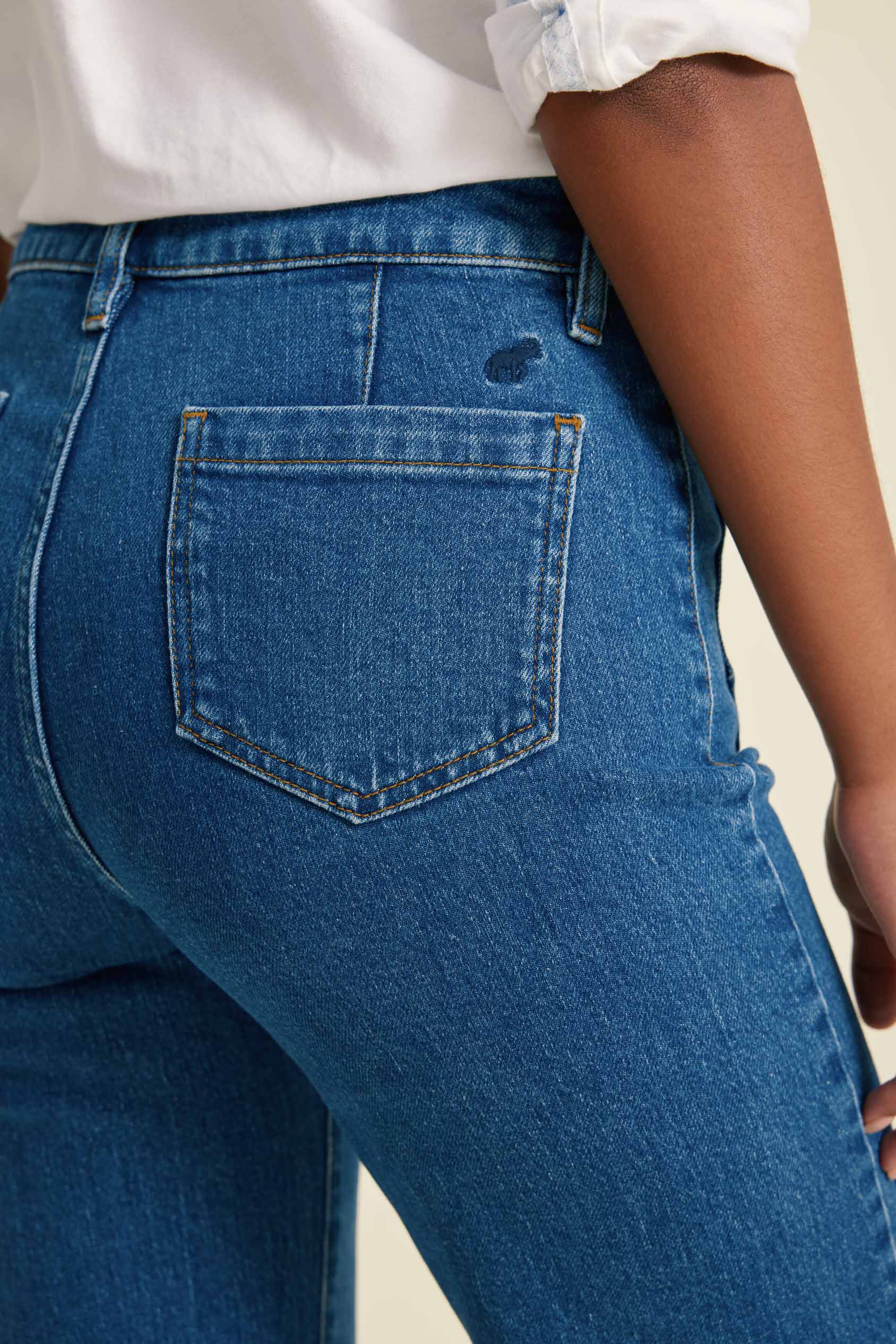 Close-up of blue jeans with a visible pocket on a plain background