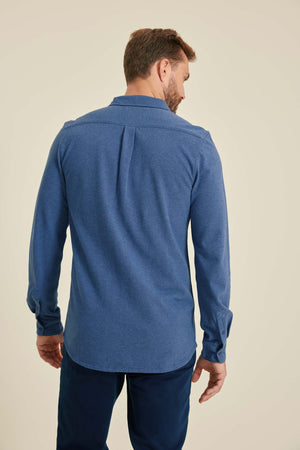 Man wearing a blue long-sleeve shirt against a beige background