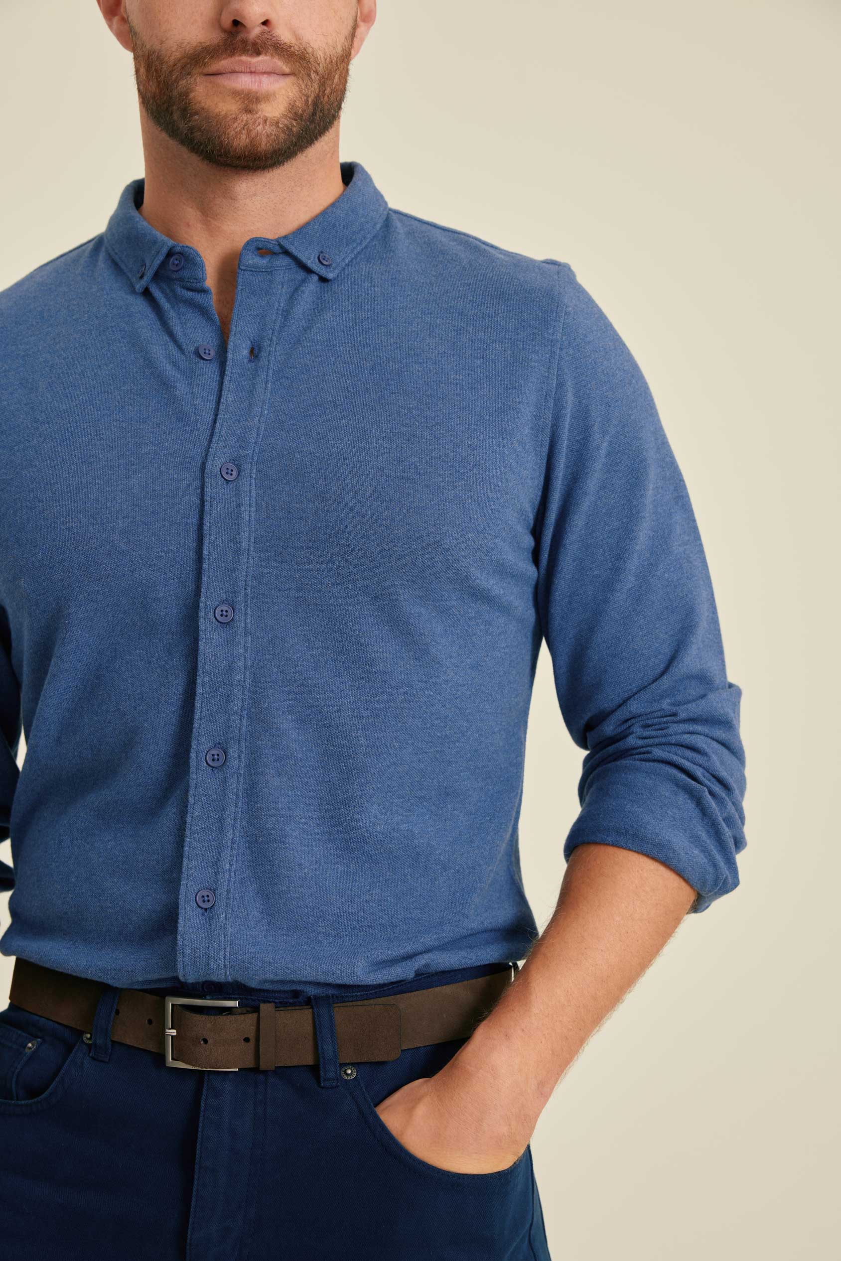 Man wearing a blue button-up shirt with a beige background