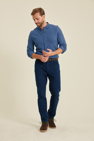 Man wearing a blue shirt and pants on a beige background