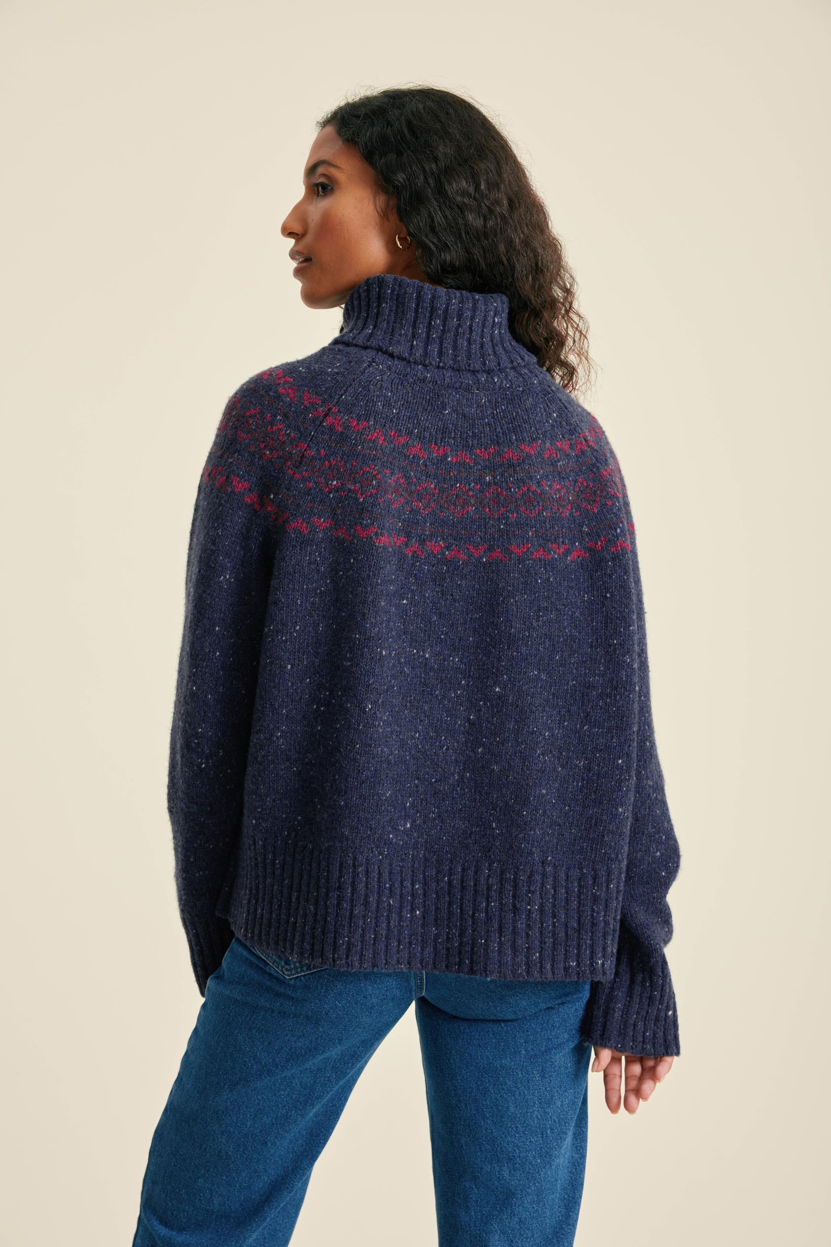 Woman wearing a blue knitted sweater with a patterned design on a beige background