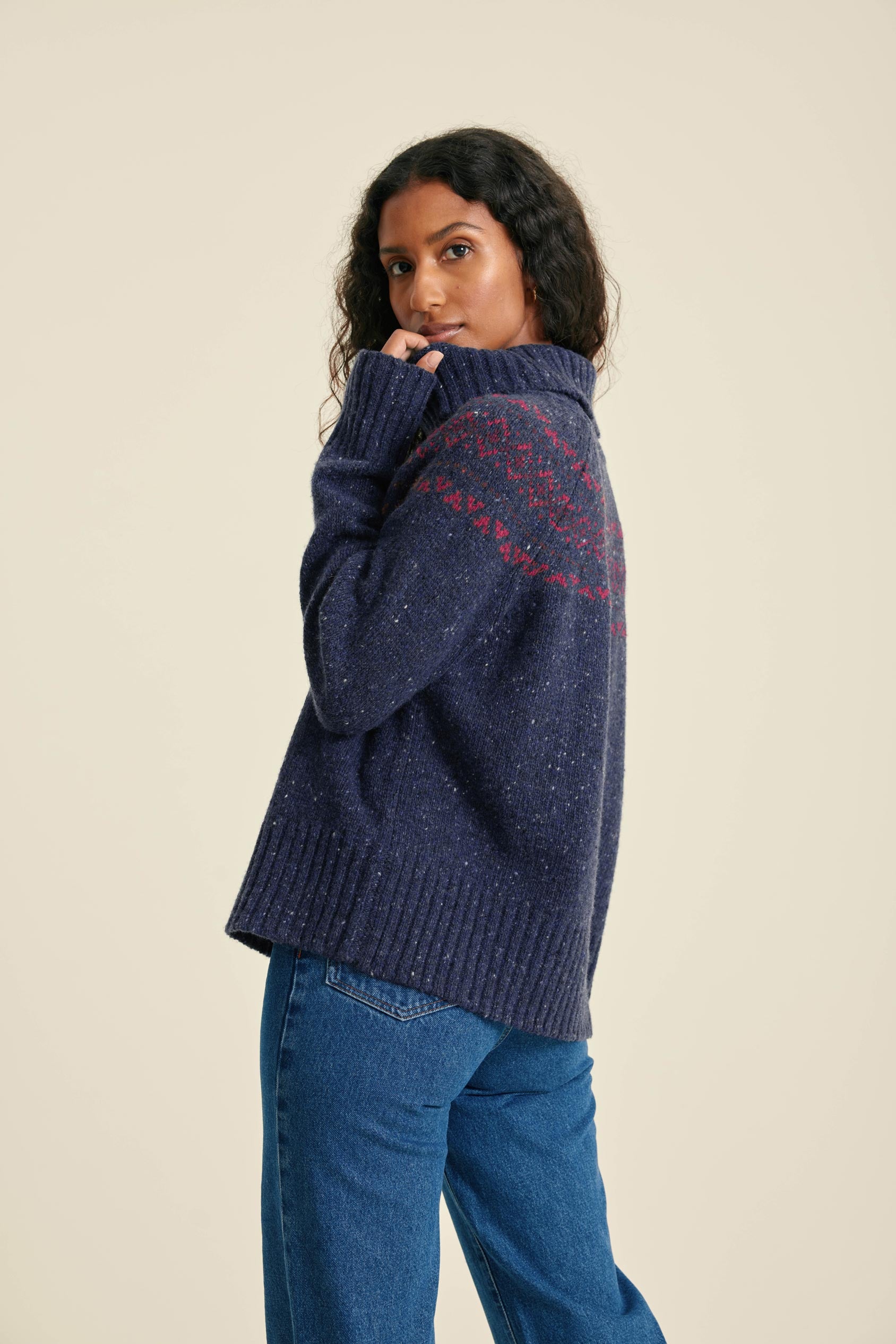 Woman wearing a navy blue sweater with text on the back against a beige background