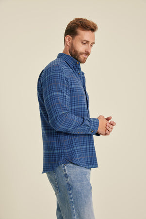 Man wearing a blue checkered shirt and jeans on a beige background