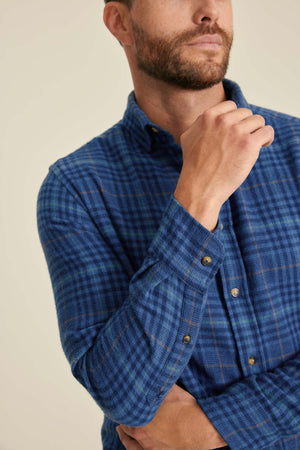 Man wearing a blue checkered shirt against a beige background