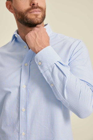 Man wearing a light blue checkered shirt against a beige background