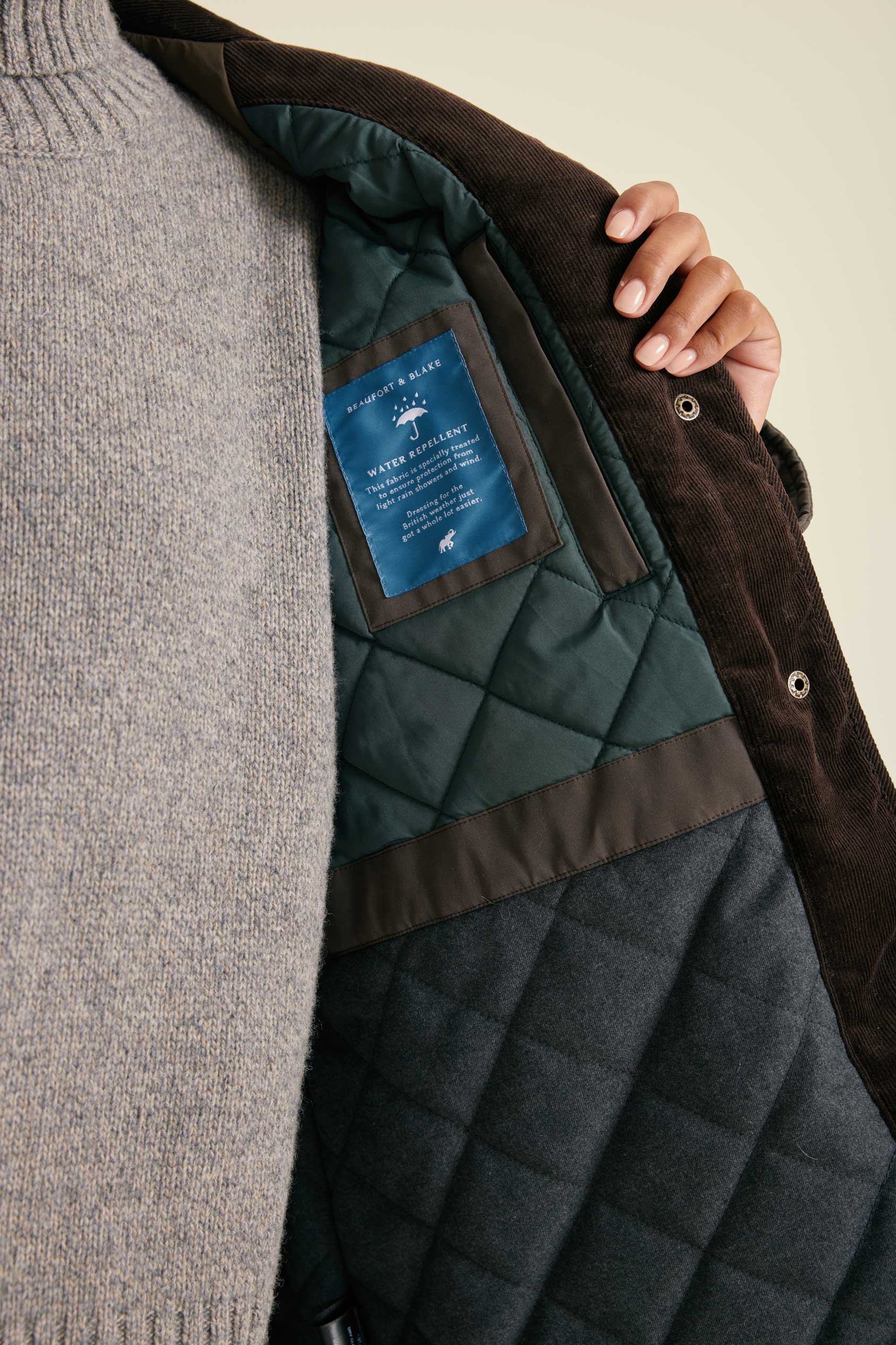 Close-up of a quilted jacket with a brand label on a neutral background