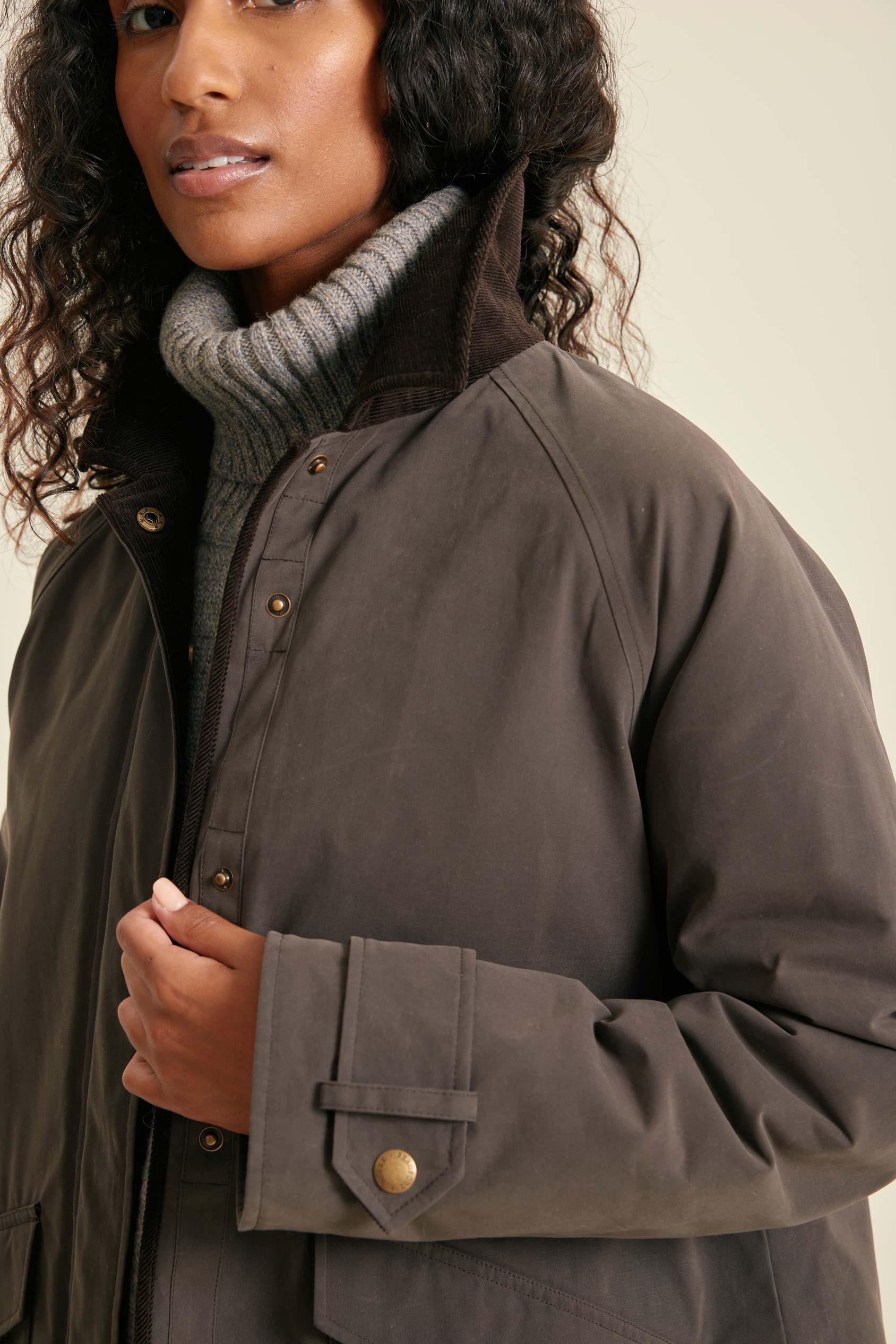 Woman wearing a brown coat with a neutral background