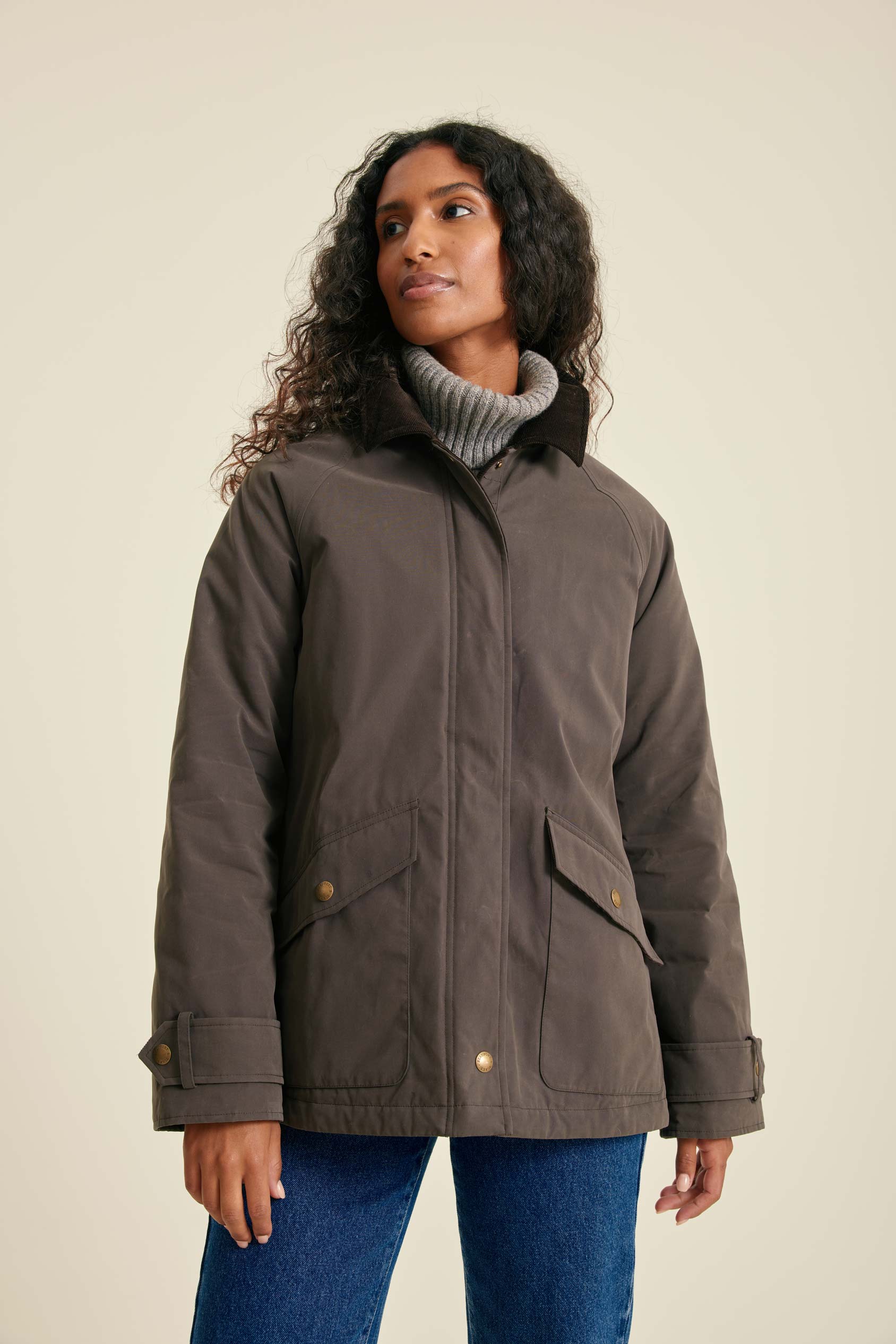 Woman wearing a brown jacket with a beige background