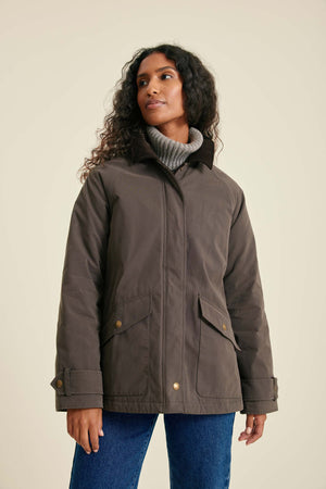 Woman wearing a brown jacket with a beige background