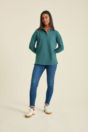 Woman wearing a pine sweatshirt and blue jeans on a beige background