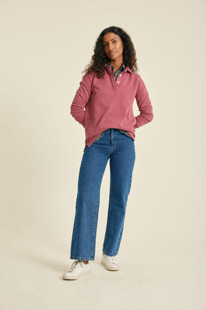 Woman wearing a pink sweat and blue jeans on a beige background