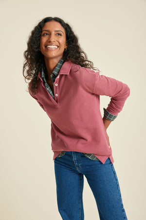 Woman wearing a pink sweatshirt with  blue jeans on a beige background