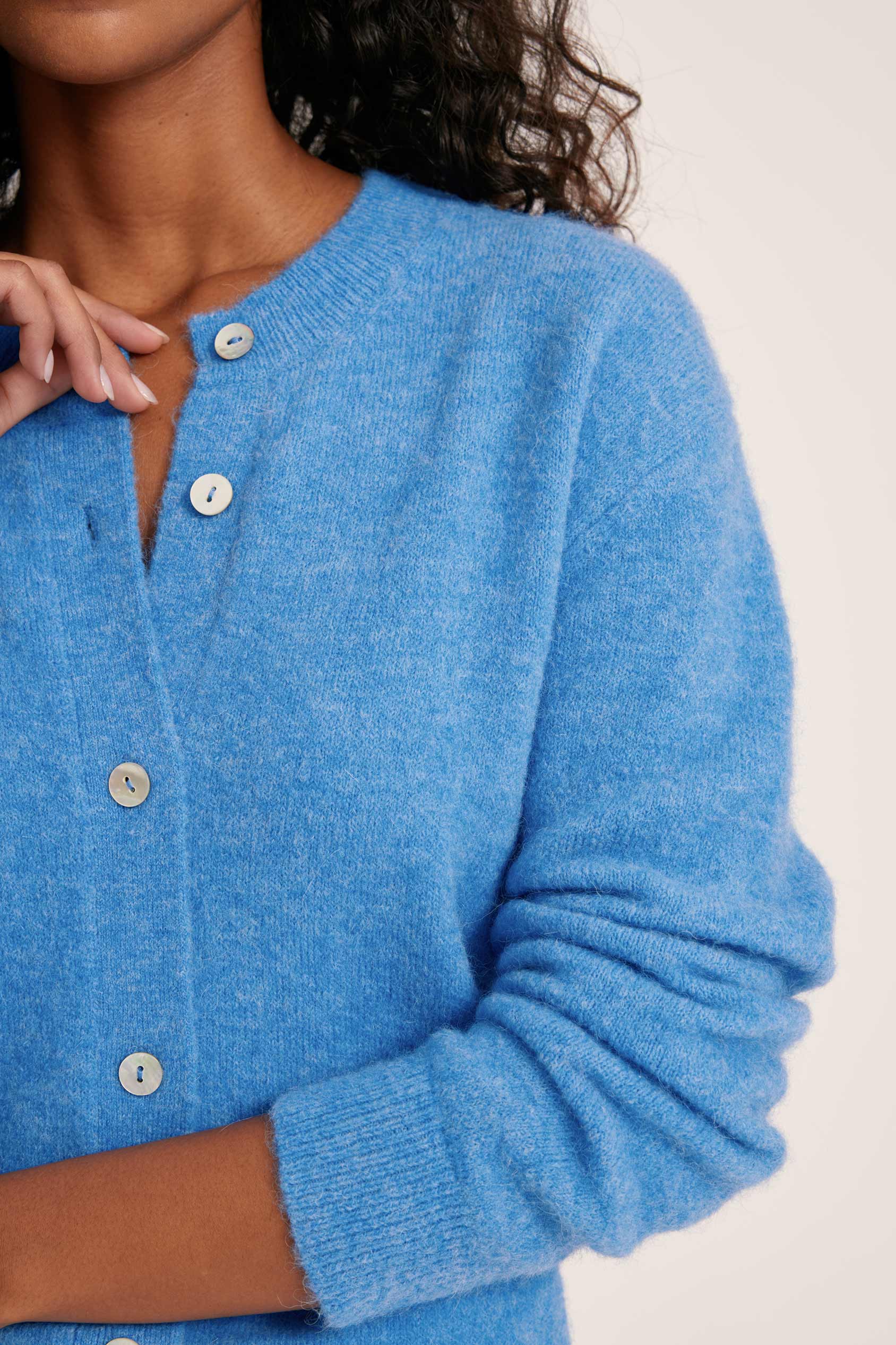 Close-up of a blue cardigan with buttons on a neutral background