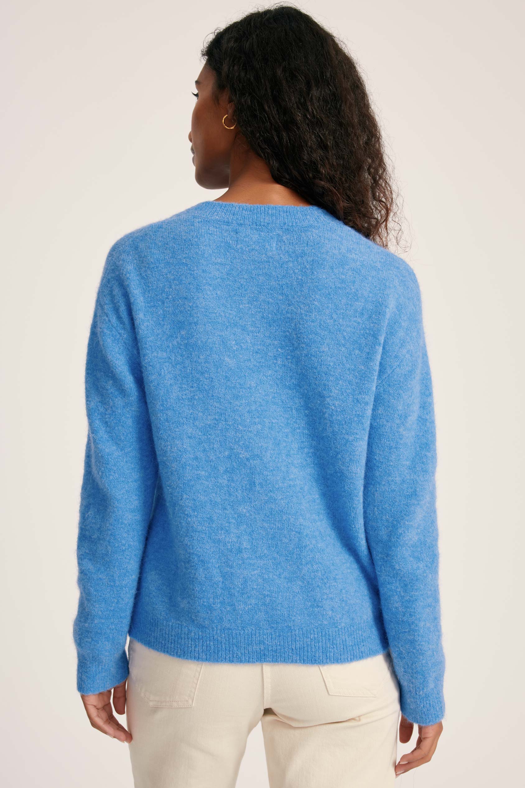 Person wearing a blue sweater on a plain background