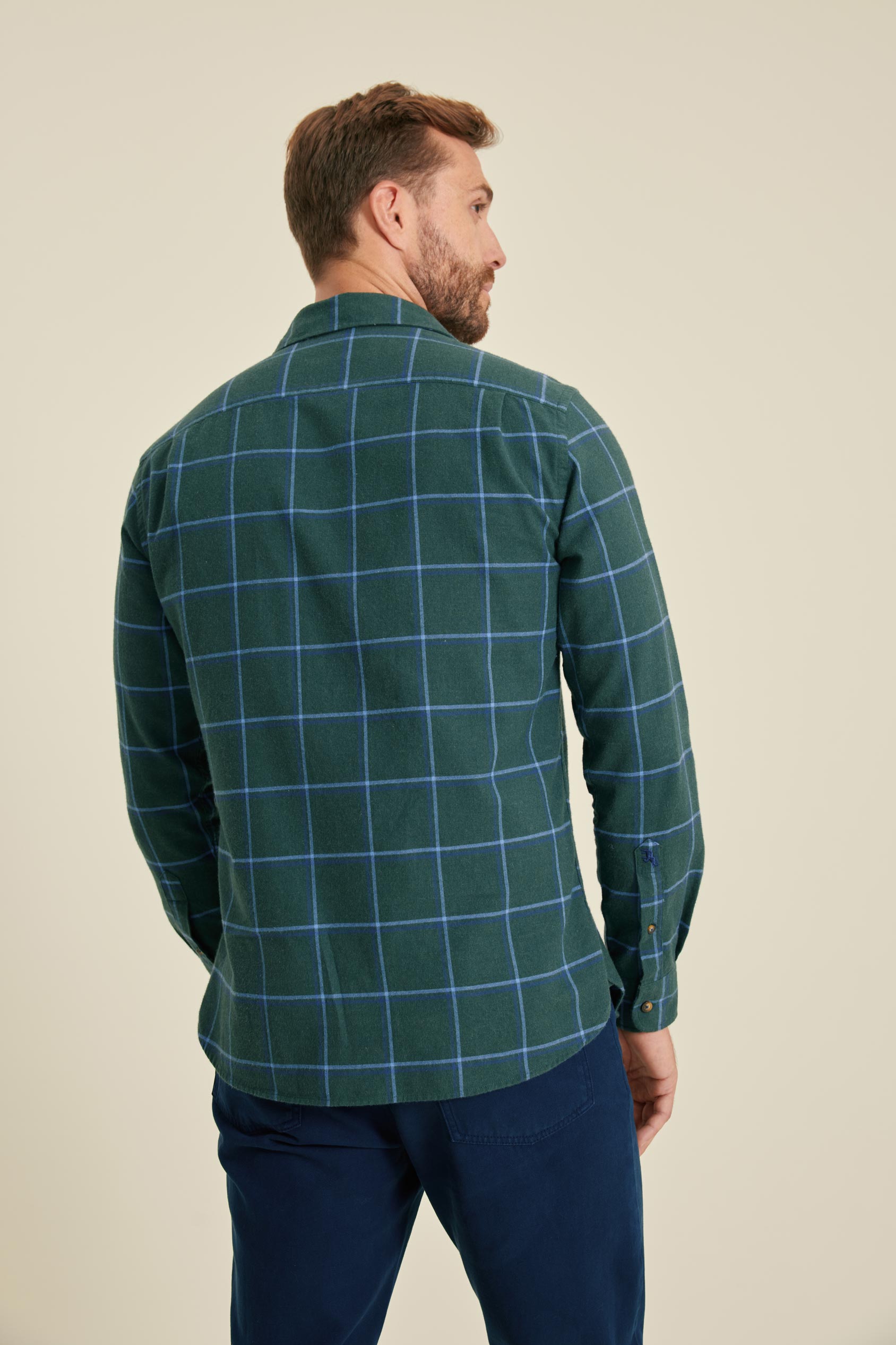 Man wearing a green checkered shirt against a beige background