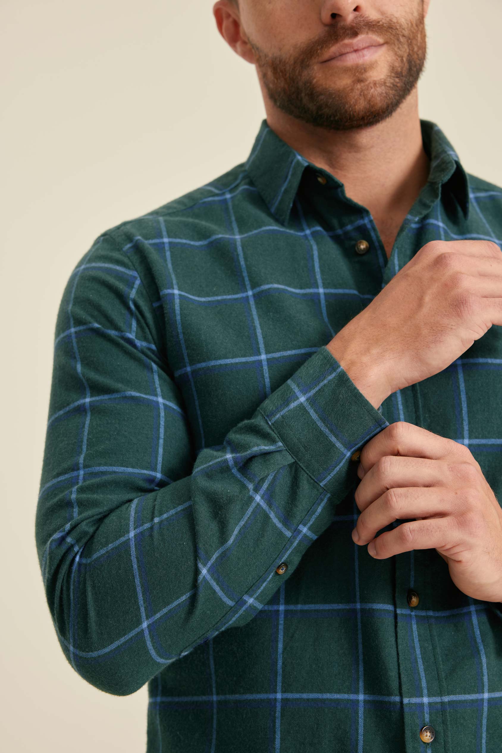 Man wearing a green checkered shirt against a beige background