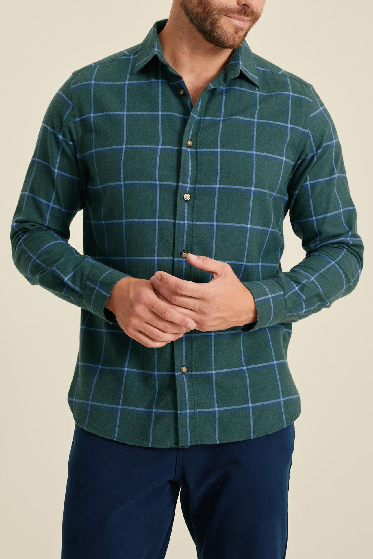 Man wearing a green checkered shirt against a beige background